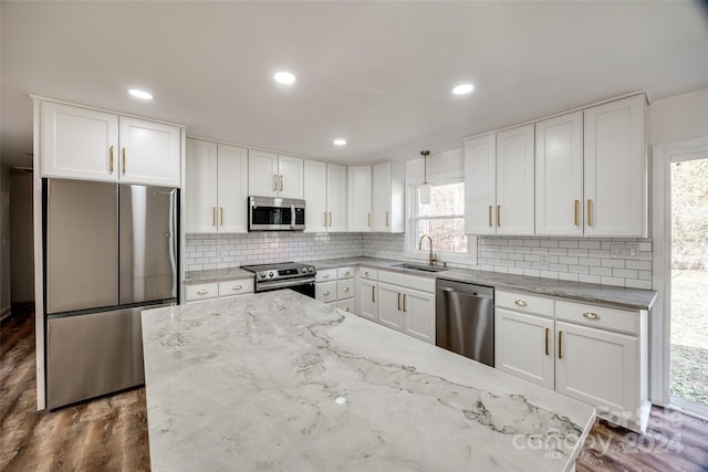 kitchen with pendant lighting, dark wood-type flooring, white cabinets, sink, and appliances with stainless steel finishes