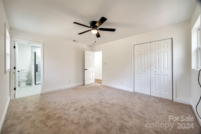 unfurnished bedroom featuring a closet, ensuite bathroom, ceiling fan, and light colored carpet