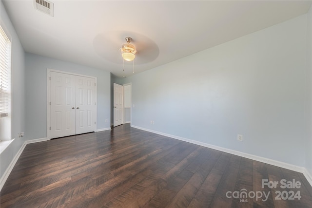 unfurnished bedroom with dark wood-type flooring, ceiling fan, and a closet