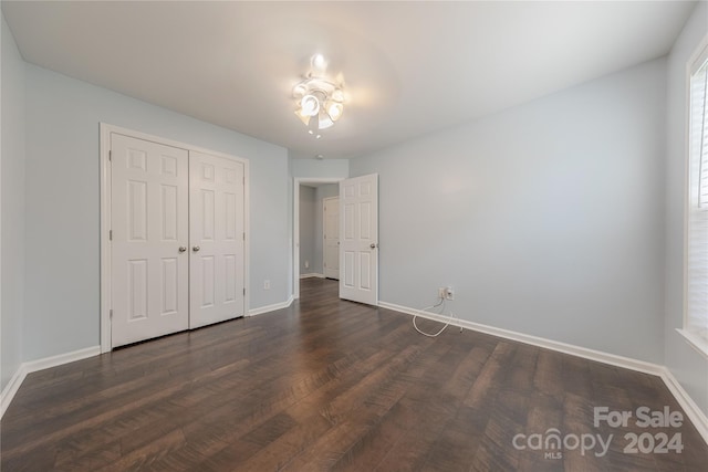 unfurnished bedroom with a closet and dark hardwood / wood-style flooring