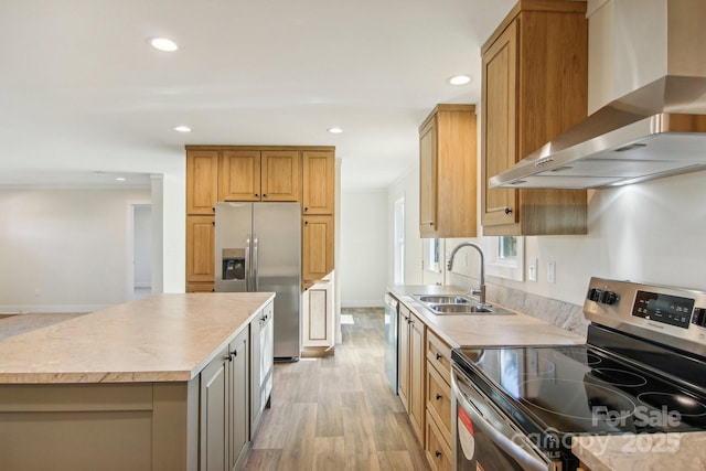 kitchen featuring a center island, sink, wall chimney exhaust hood, appliances with stainless steel finishes, and light hardwood / wood-style floors