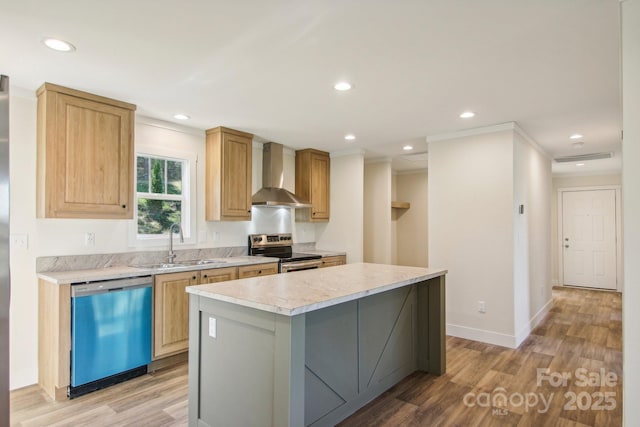 kitchen featuring wall chimney range hood, sink, light hardwood / wood-style flooring, appliances with stainless steel finishes, and a kitchen island