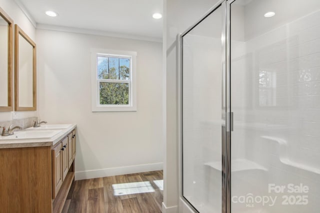 bathroom with hardwood / wood-style floors, vanity, a shower with door, and ornamental molding