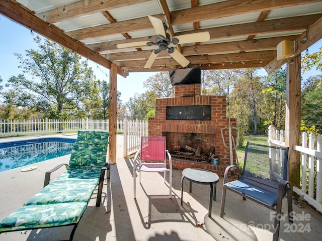 view of patio featuring an outdoor brick fireplace, ceiling fan, and a fenced in pool