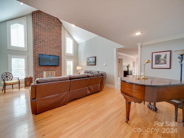 living room with light hardwood / wood-style flooring, a textured ceiling, high vaulted ceiling, and decorative columns