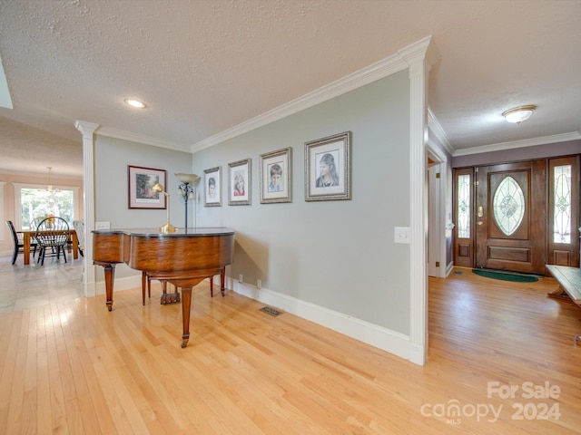 entryway featuring a chandelier, crown molding, a textured ceiling, and light hardwood / wood-style floors