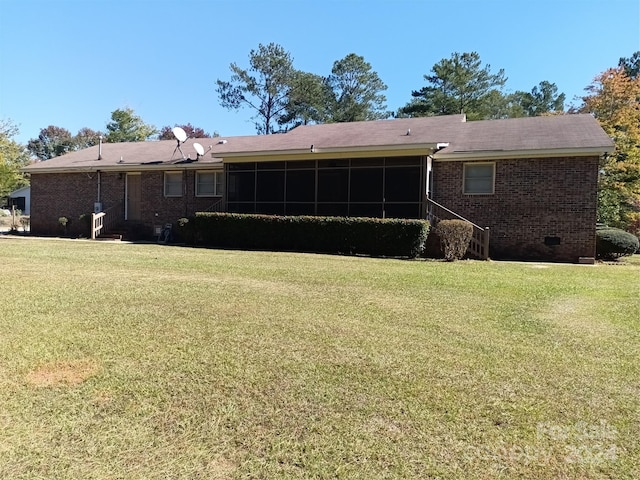 back of house featuring a sunroom and a lawn