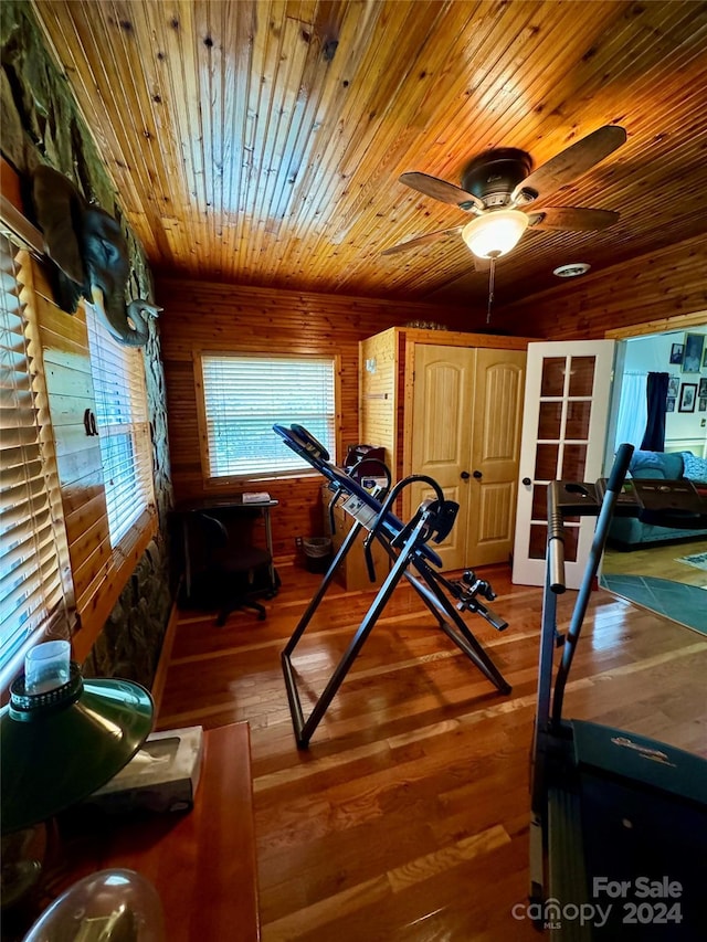 workout room with ceiling fan, wood-type flooring, wooden walls, and wooden ceiling