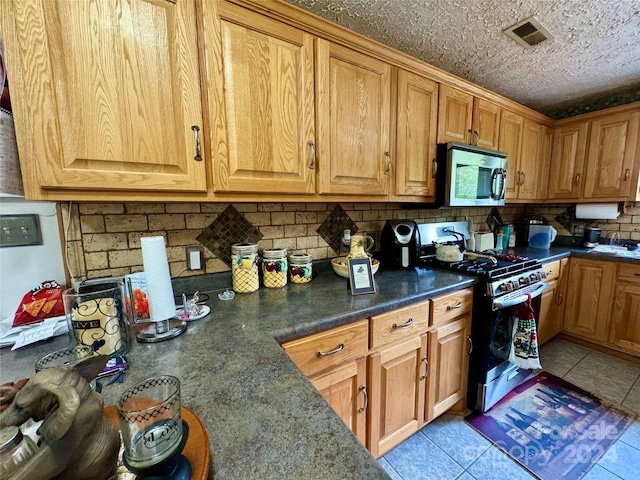 kitchen with tasteful backsplash, light tile patterned floors, stainless steel appliances, and a textured ceiling