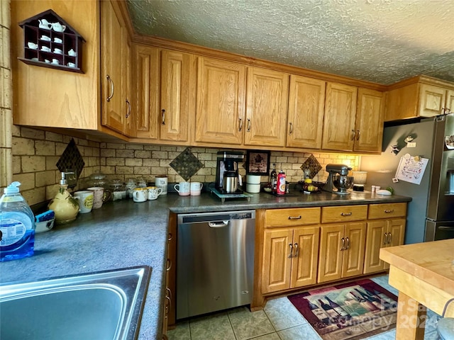 kitchen featuring sink, backsplash, a textured ceiling, light tile patterned floors, and appliances with stainless steel finishes