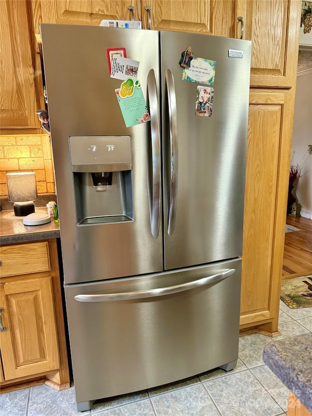 kitchen with stainless steel fridge, backsplash, and light tile patterned floors