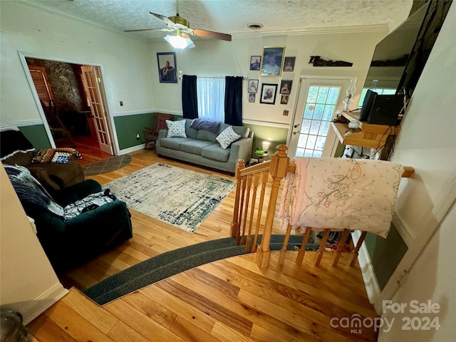 living room featuring hardwood / wood-style floors, a textured ceiling, and ornamental molding