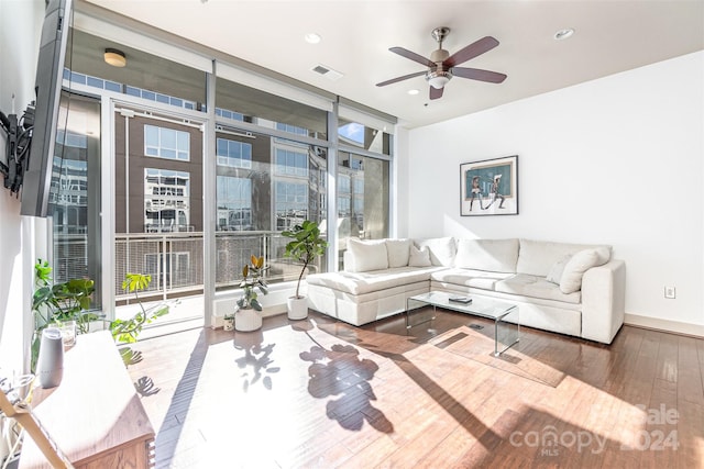 living room with ceiling fan, a healthy amount of sunlight, expansive windows, and hardwood / wood-style floors