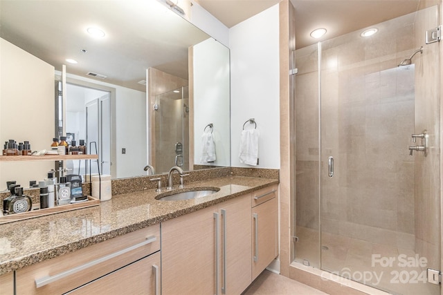 bathroom featuring a shower with door and vanity