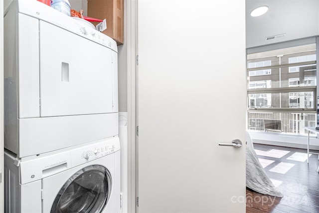 laundry area with stacked washer / dryer and wood-type flooring