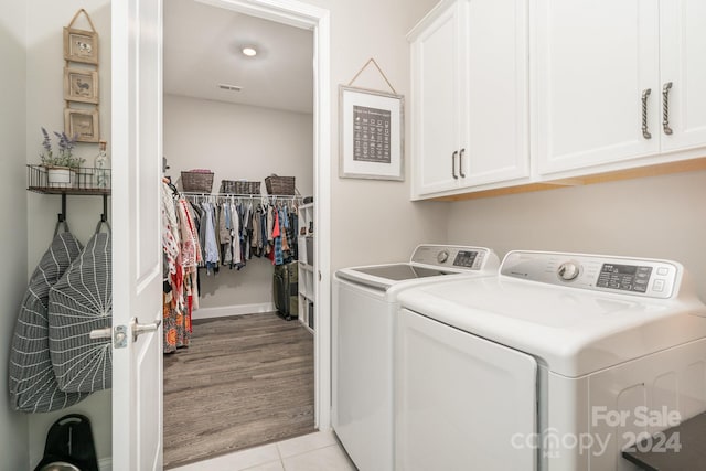 clothes washing area with light wood-type flooring, cabinets, and washer and dryer