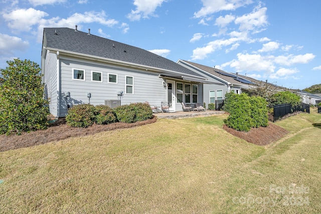 rear view of property featuring central AC unit and a lawn