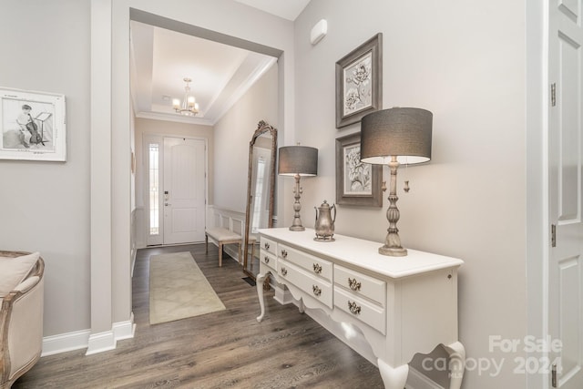 entryway featuring dark wood-type flooring, a notable chandelier, and ornamental molding