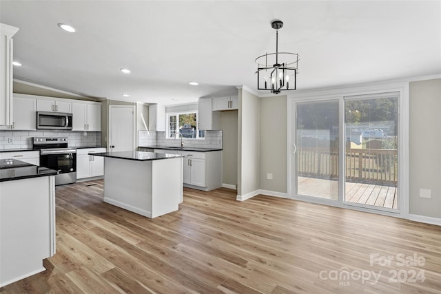 kitchen featuring appliances with stainless steel finishes, light wood-type flooring, hanging light fixtures, white cabinetry, and crown molding