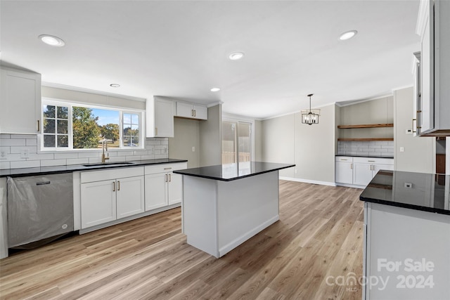 kitchen featuring white cabinets, stainless steel dishwasher, light hardwood / wood-style flooring, decorative light fixtures, and sink