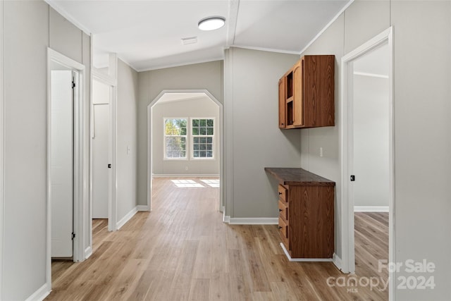 hall featuring light hardwood / wood-style floors, lofted ceiling, and ornamental molding