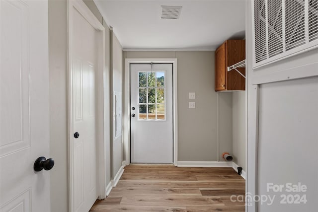 clothes washing area with light hardwood / wood-style floors and cabinets