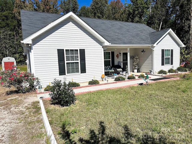 ranch-style home featuring a storage shed, a front lawn, and a porch