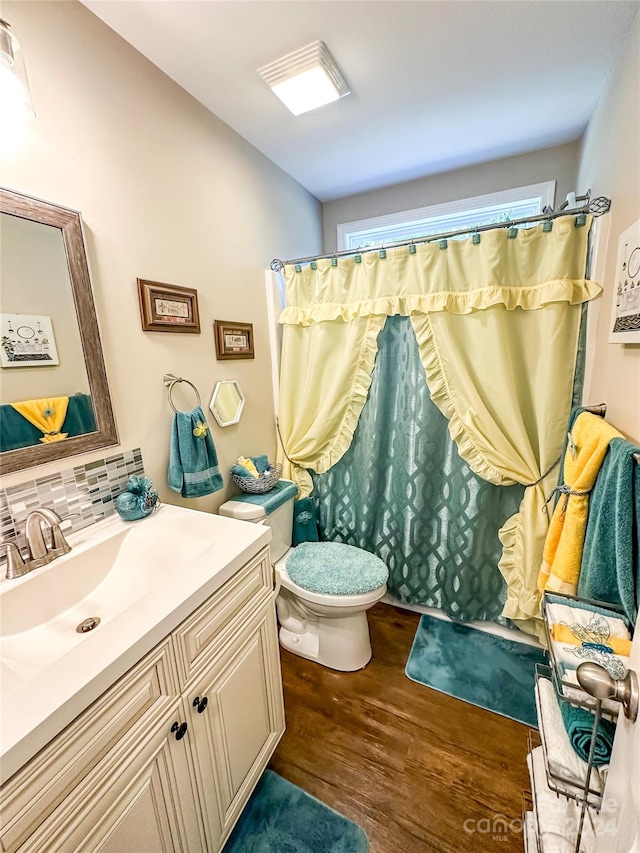 bathroom featuring toilet, wood-type flooring, curtained shower, vanity, and tasteful backsplash