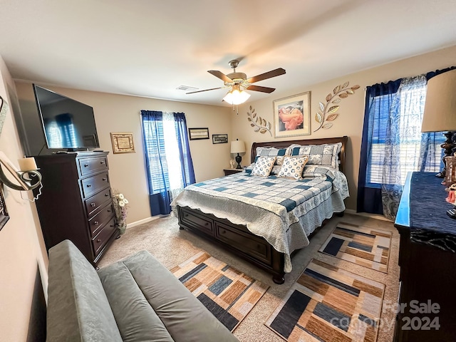 bedroom with ceiling fan, multiple windows, and light colored carpet