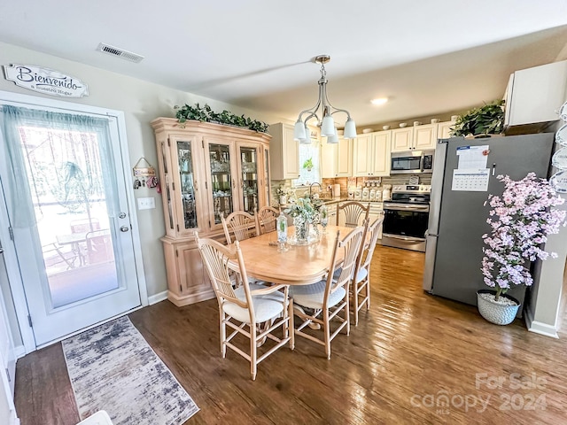 dining room featuring sink, dark hardwood / wood-style flooring, and a chandelier