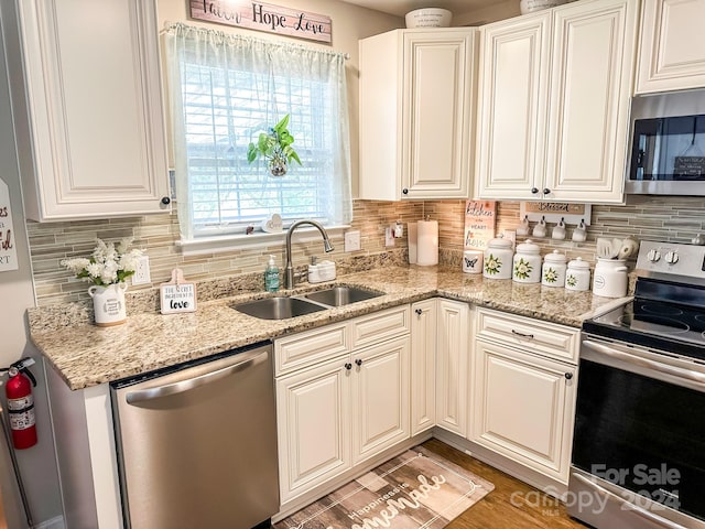 kitchen featuring tasteful backsplash, light stone countertops, sink, stainless steel appliances, and white cabinets