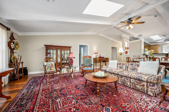 living room featuring lofted ceiling with skylight, hardwood / wood-style floors, and ceiling fan