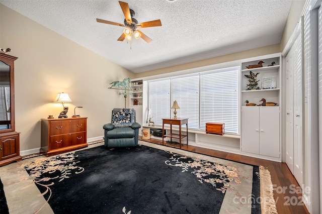 sitting room featuring ceiling fan, wood-type flooring, a textured ceiling, and a baseboard heating unit