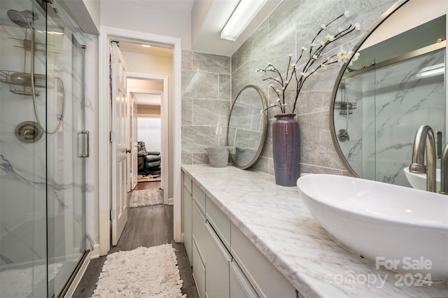 bathroom with vanity, hardwood / wood-style floors, a shower with shower door, and tile walls