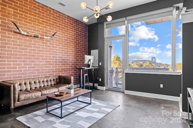 living room with a notable chandelier, brick wall, and plenty of natural light