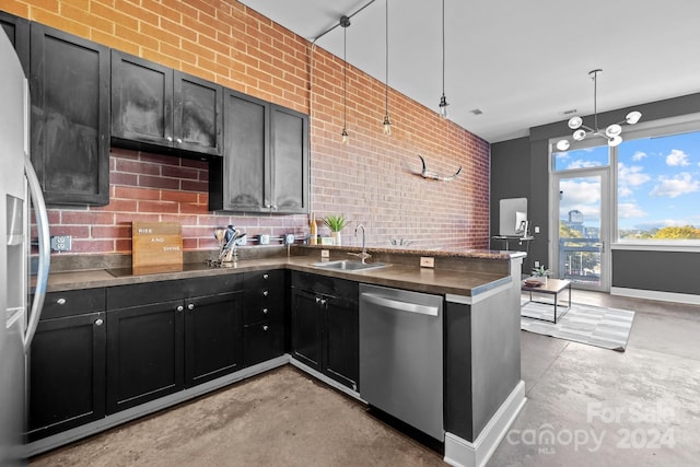 kitchen featuring stainless steel appliances, sink, pendant lighting, and brick wall