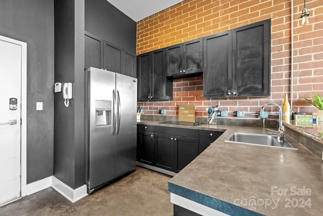 kitchen featuring sink, brick wall, stainless steel fridge with ice dispenser, and black electric stovetop