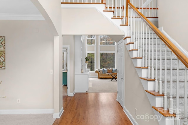 stairs featuring wood-type flooring and ornamental molding