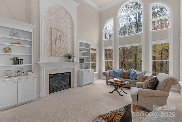 carpeted living room with a wealth of natural light, a high ceiling, and ornamental molding