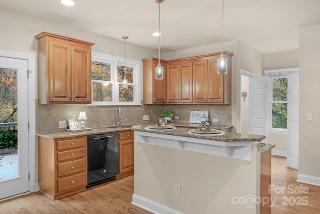 kitchen with pendant lighting, dishwasher, light stone counters, and backsplash