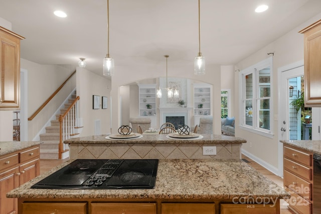 kitchen featuring light stone countertops, light hardwood / wood-style flooring, black appliances, and decorative light fixtures