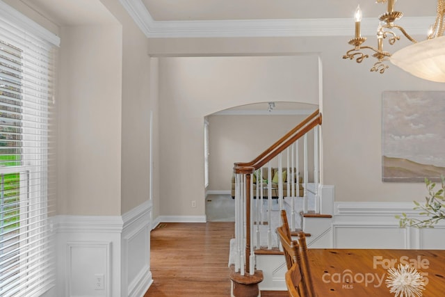 interior space featuring hardwood / wood-style flooring, ornamental molding, and a notable chandelier