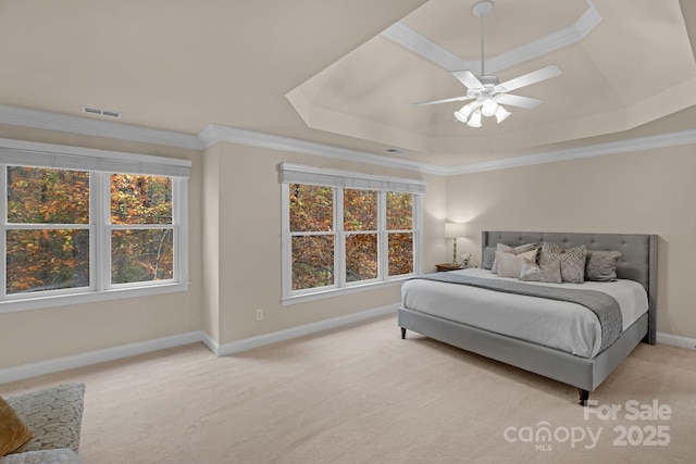 bedroom featuring a raised ceiling, ceiling fan, ornamental molding, multiple windows, and light colored carpet