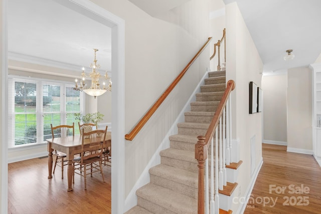 staircase featuring hardwood / wood-style flooring and an inviting chandelier