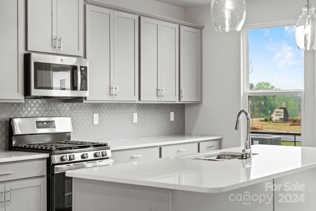 kitchen with gray cabinetry, tasteful backsplash, sink, stainless steel appliances, and decorative light fixtures