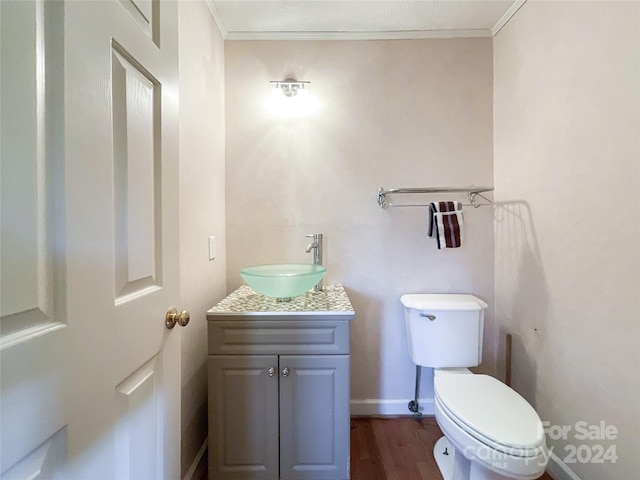 bathroom with vanity, toilet, crown molding, and hardwood / wood-style floors