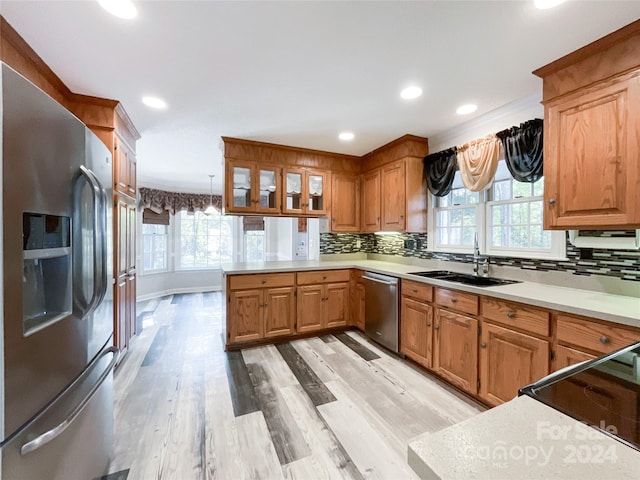 kitchen featuring tasteful backsplash, sink, pendant lighting, light hardwood / wood-style floors, and stainless steel appliances