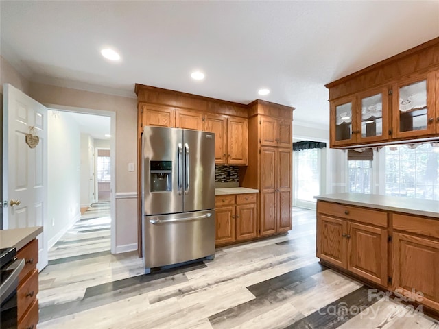 kitchen featuring appliances with stainless steel finishes, ornamental molding, backsplash, and light hardwood / wood-style floors