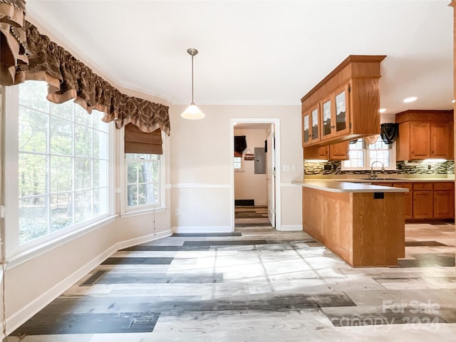 kitchen featuring kitchen peninsula, tasteful backsplash, a breakfast bar, light wood-type flooring, and pendant lighting