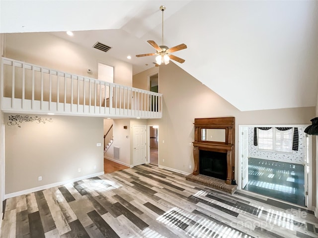 unfurnished living room with ceiling fan, high vaulted ceiling, and hardwood / wood-style floors